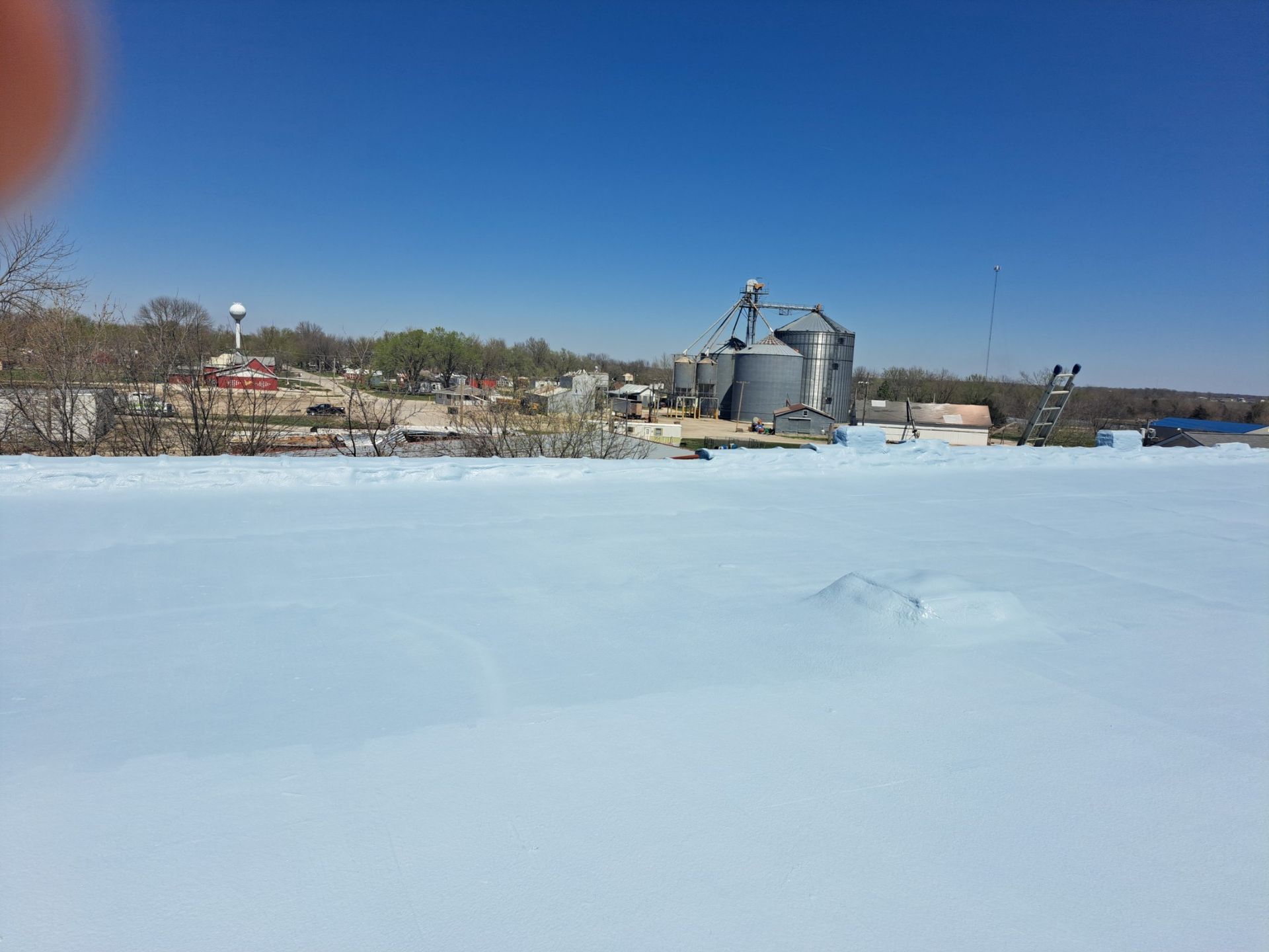 A large snow covered field with a factory in the background.