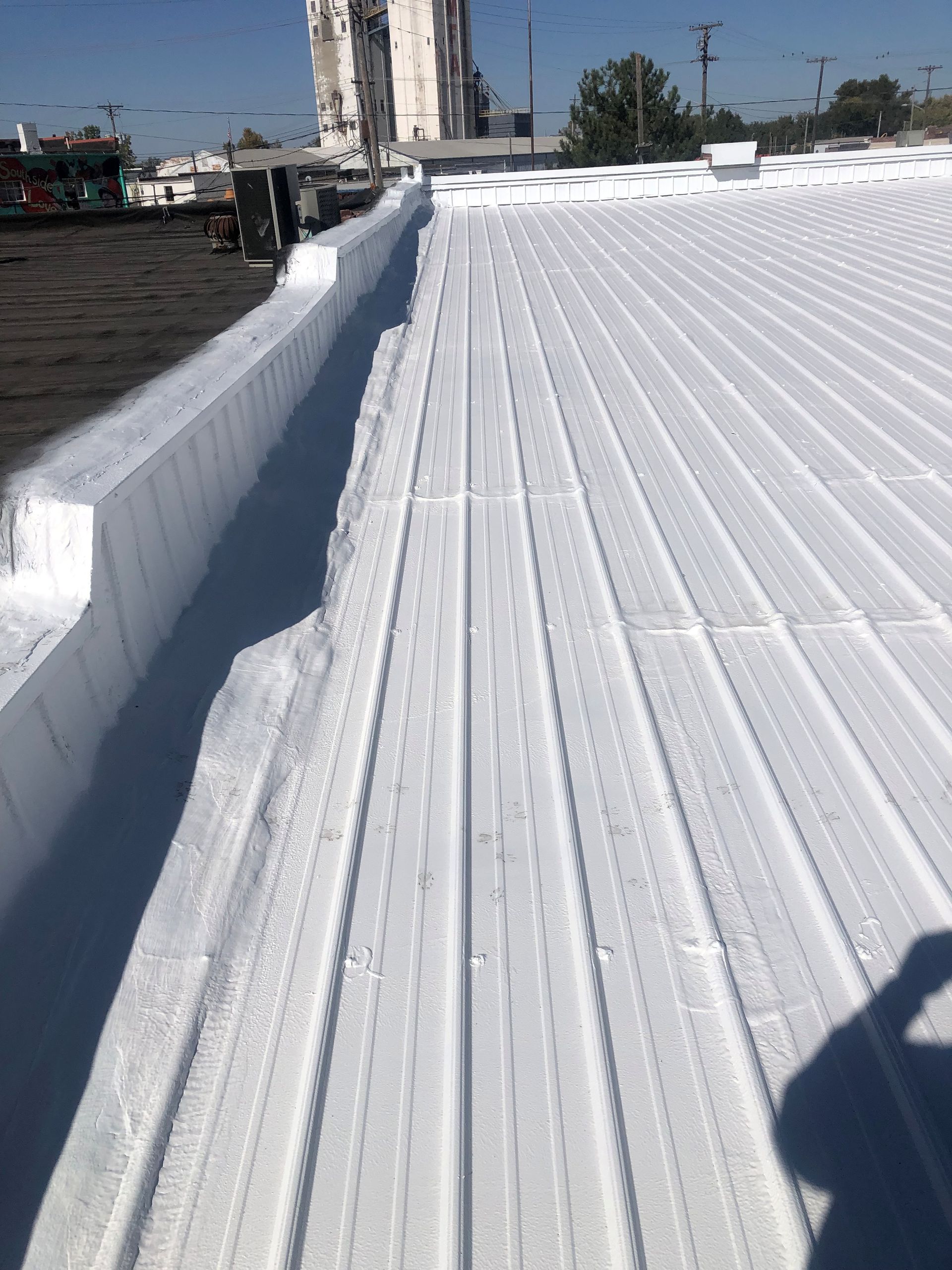 A white roof with a drain on the side of it.