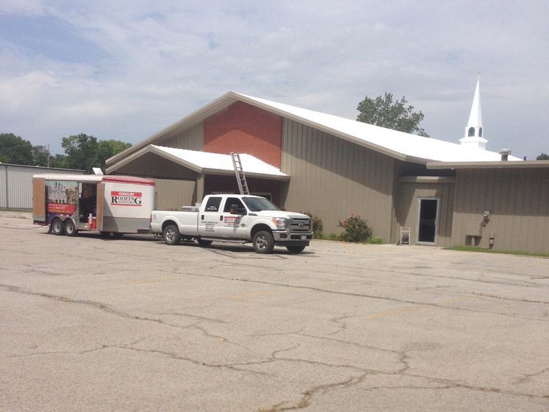 A white truck is parked in front of a large building