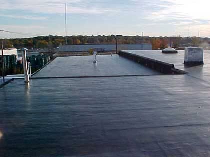 A large black roof with a chimney on top of it.
