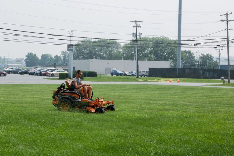 A man is riding a lawn mower on a lush green field.