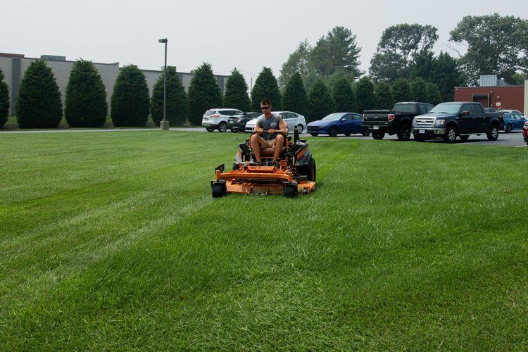 A man is riding a lawn mower on a lush green field.