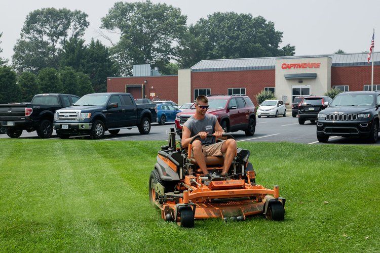 A man is riding a lawn mower on a lush green field.