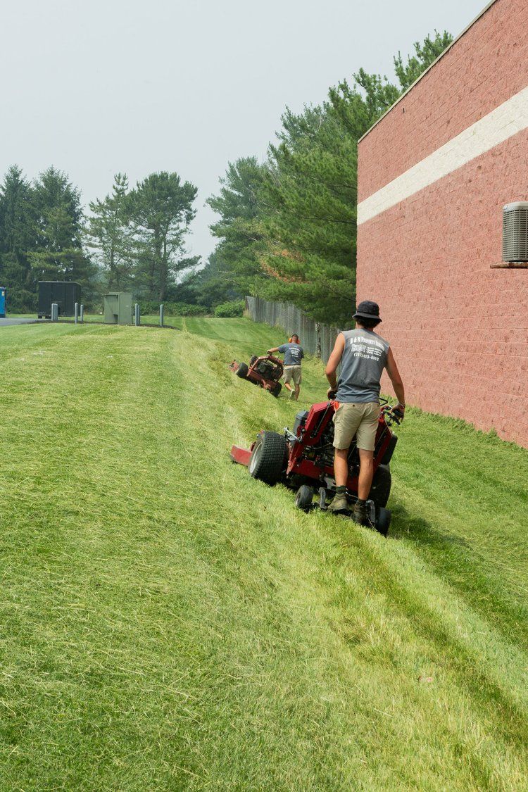 A man is riding a lawn mower on a lush green field.
