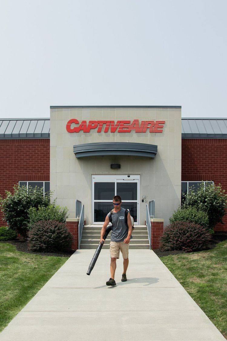 A man is walking down a sidewalk in front of a building that says captivate