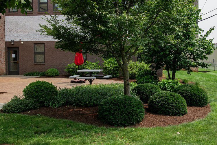 A picnic table with an umbrella in front of a building