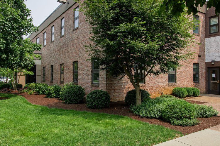 A large brick building with a lush green lawn in front of it.