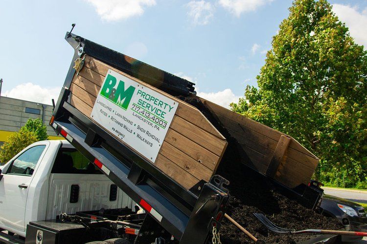 A dumpster is being loaded into the back of a truck.