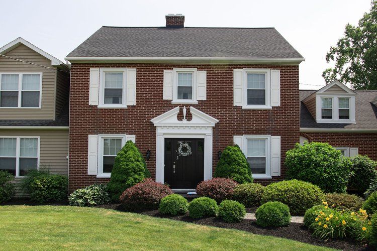 A brick house with white shutters and a wreath on the door