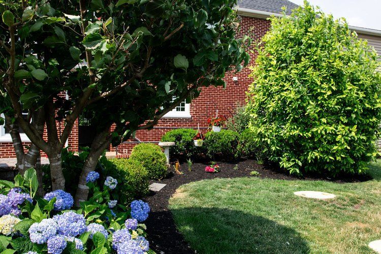 A brick house with a lush green lawn and flowers in front of it.