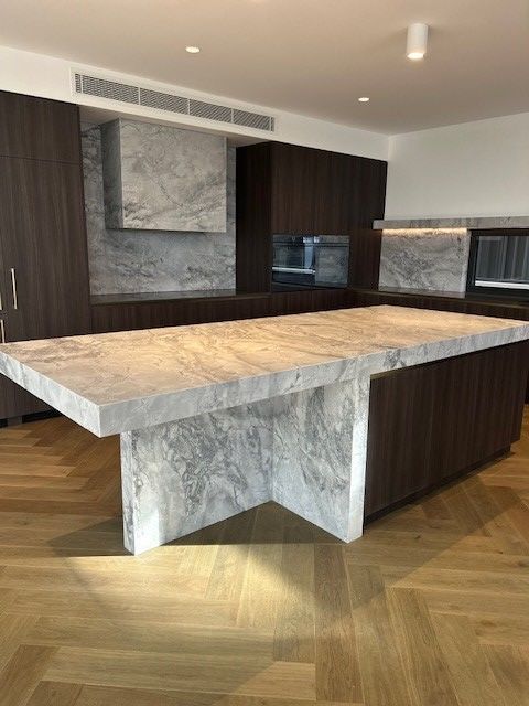 A Kitchen with Black Cabinets and A Large Island in The Middle — Inovative Interiors In Cardiff, NSW
