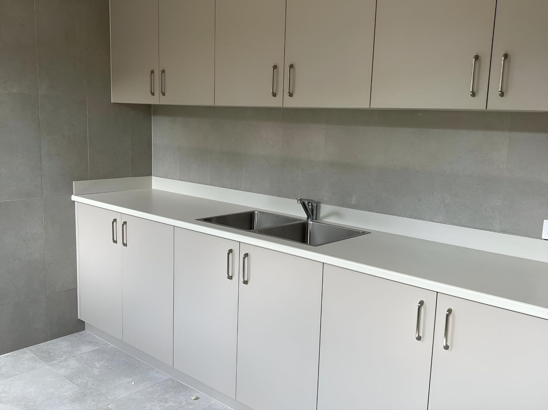 An Empty Kitchen with White Cabinets and A Sink  — Inovative Interiors In Cardiff, NSW