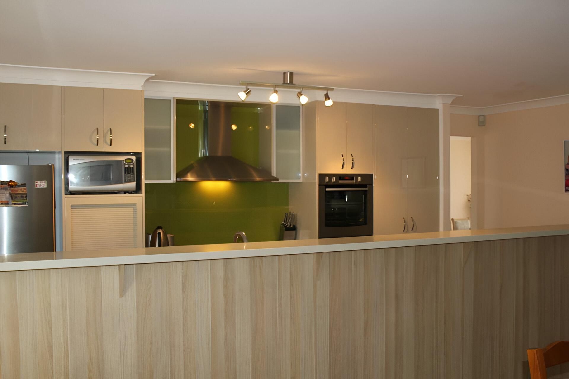 A Kitchen with Stainless Steel Appliances and Wooden Cabinets — Inovative Interiors In Cardiff, NSW