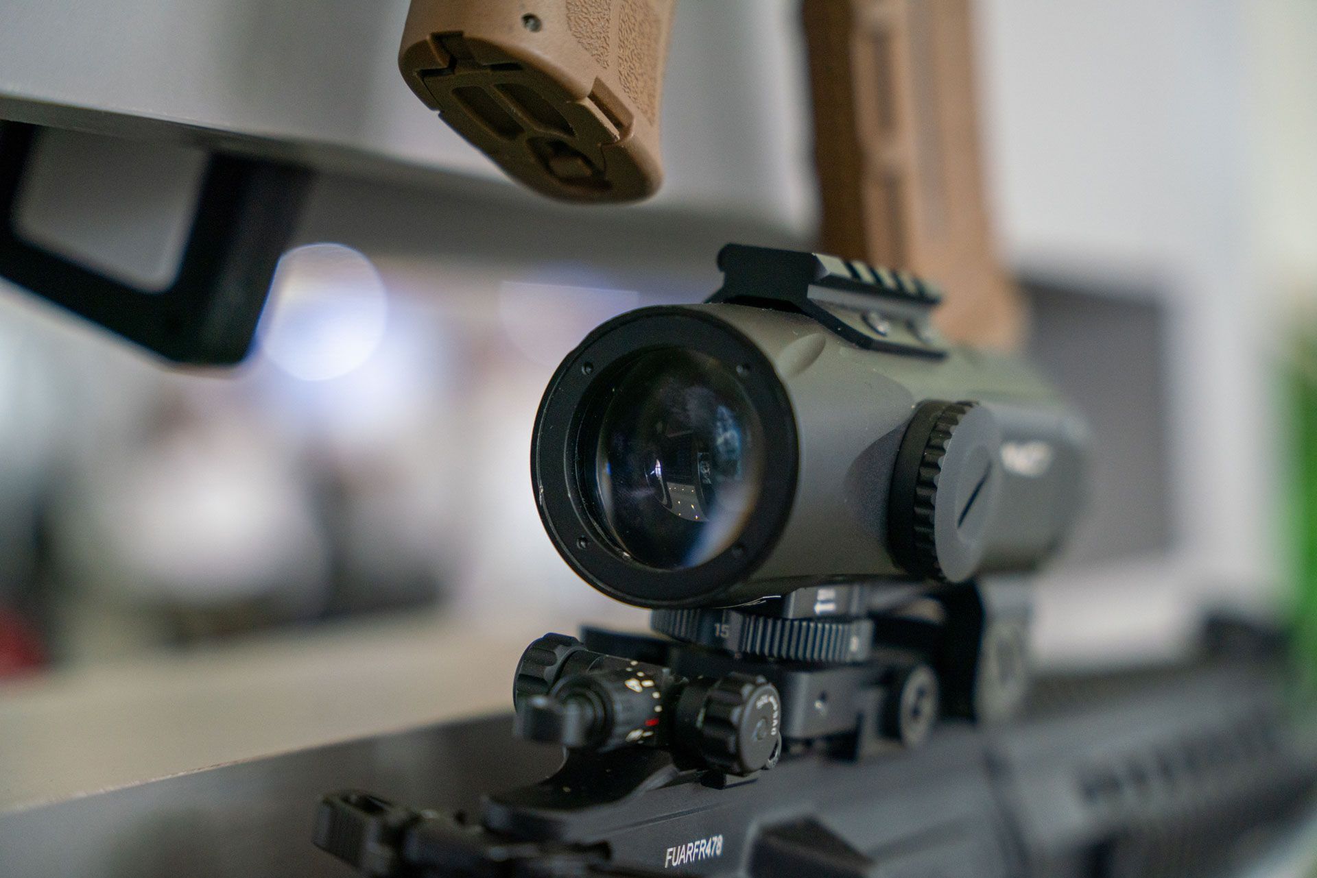 Close-up of a tactical scope mounted on a rifle, with a blurred background.