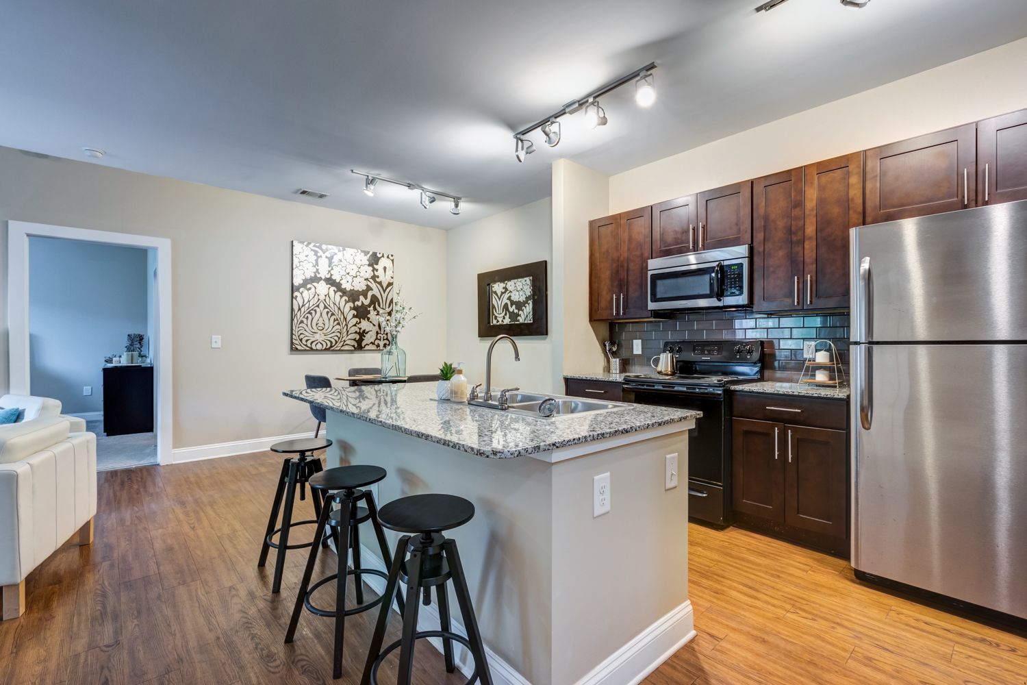 Open-concept kitchen with an island, stainless steel appliances, and dark wood cabinets at Arcadia's Edge in Columbia, SC.