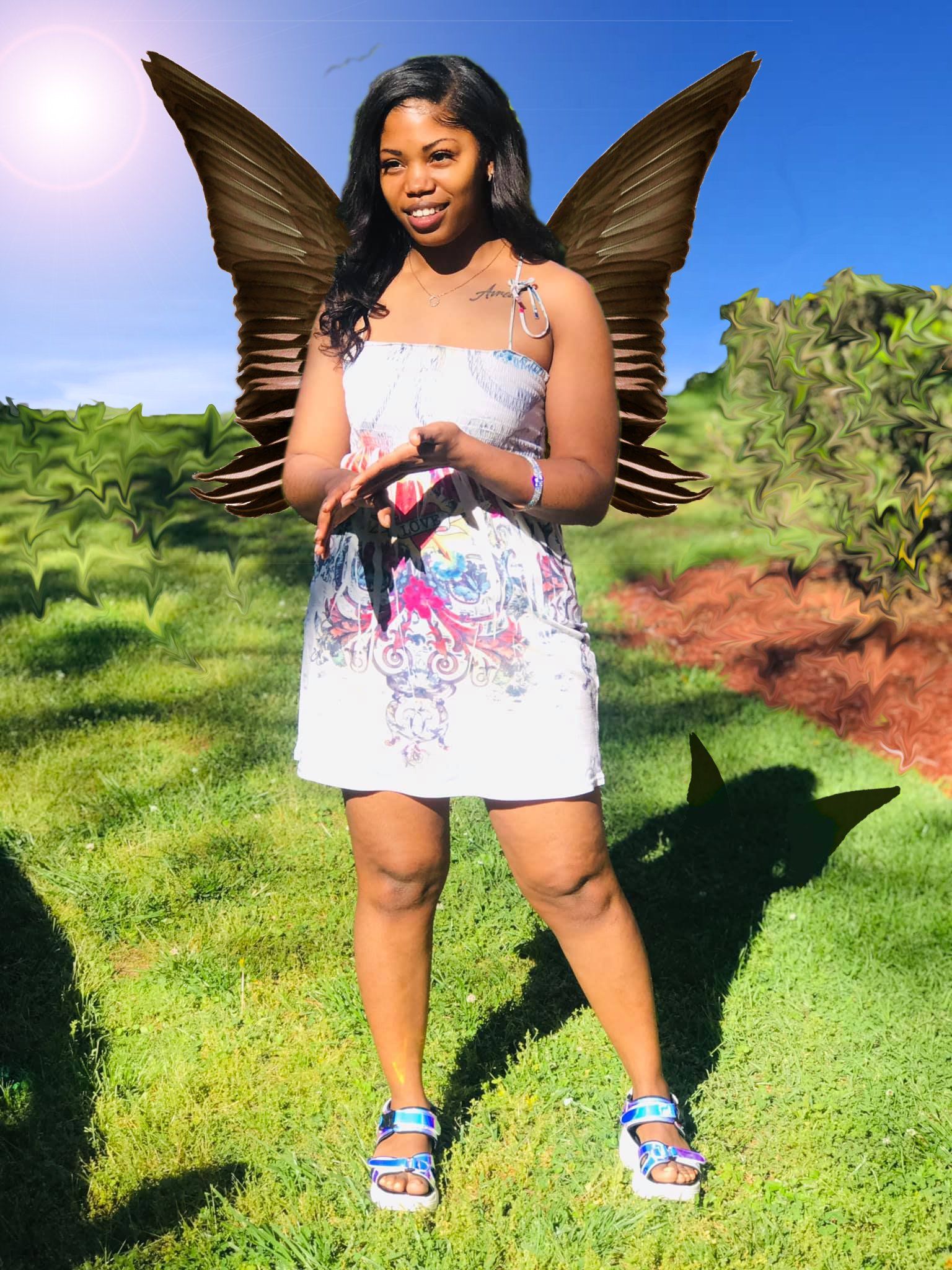 Image of a woman wearing a butterfly wings with a nature background