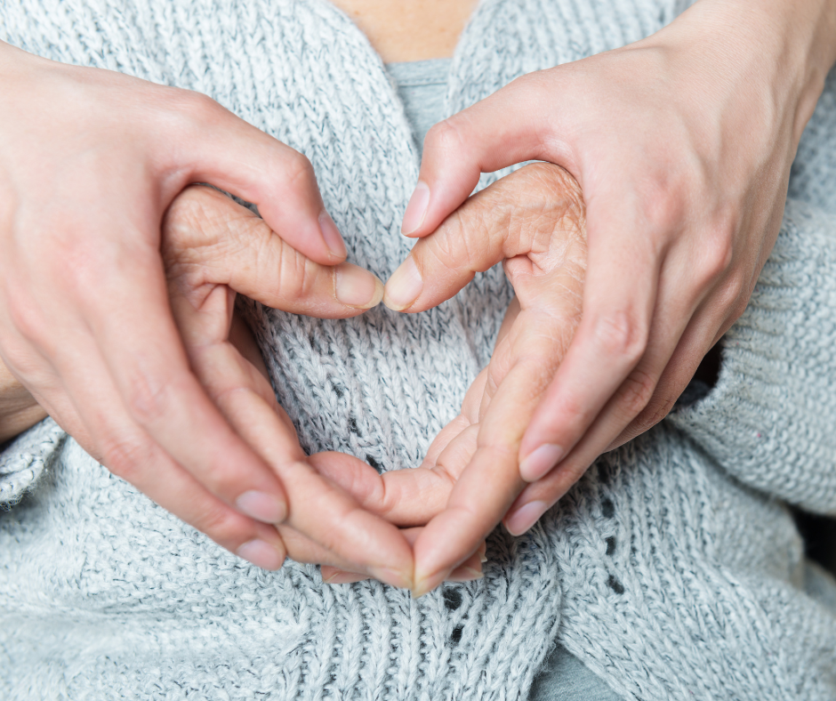 Close-up of two pairs of hands forming a heart shape, symbolizing care and support.