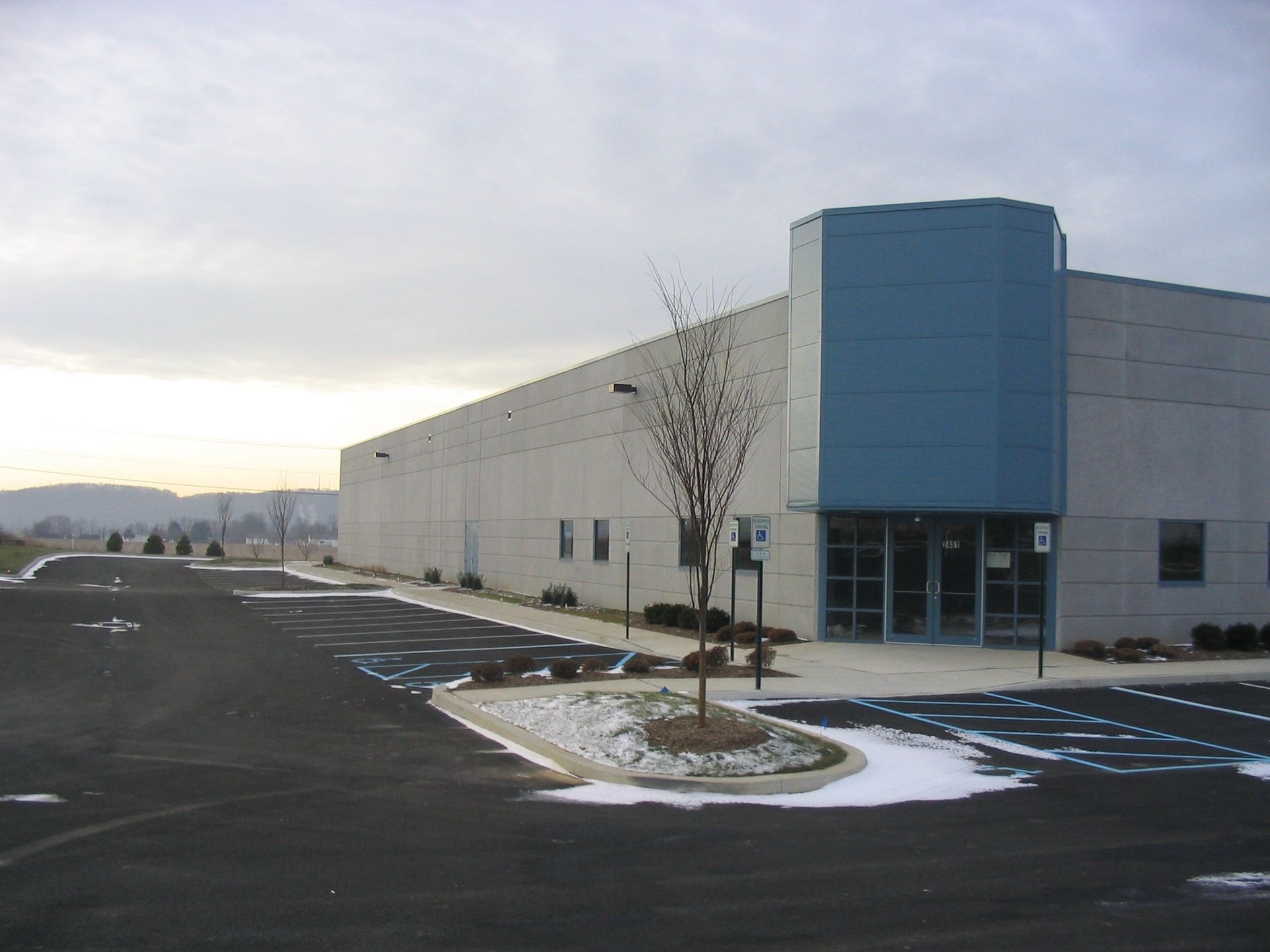 A stairwell with red railings and a large glass window wall overlooking a road, trees, and landscaping.