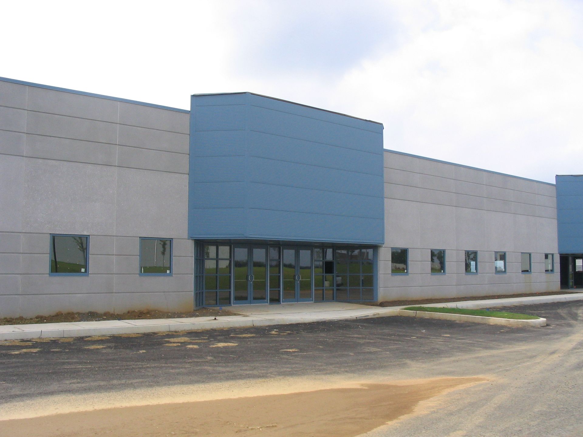 A modern, low-rise brick commercial building with a large grid-pattern glass window, red trim, and a centered entrance.