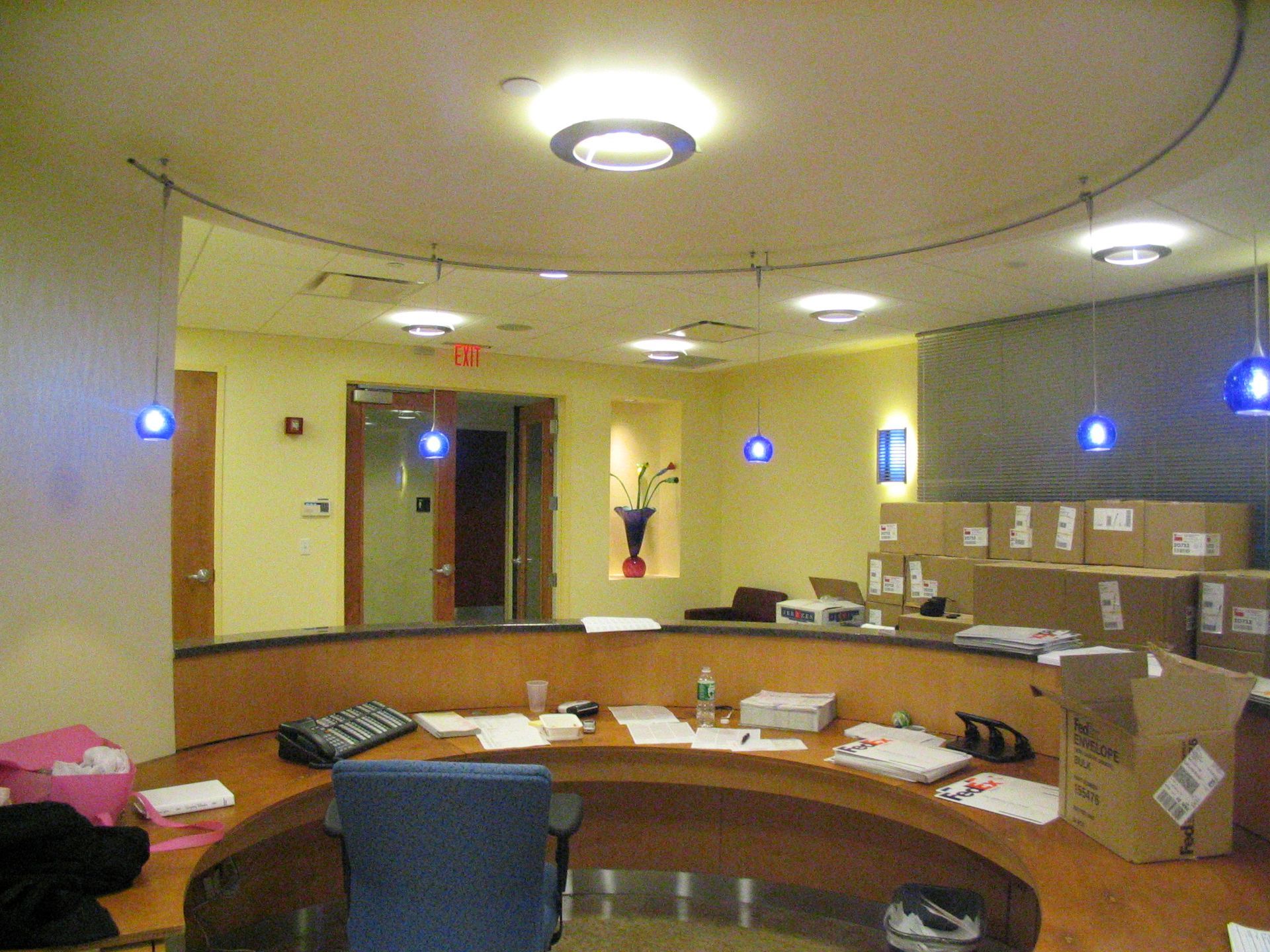 A wooden reception desk stands in an office lobby with green walls, a black armchair, and a small American flag.
