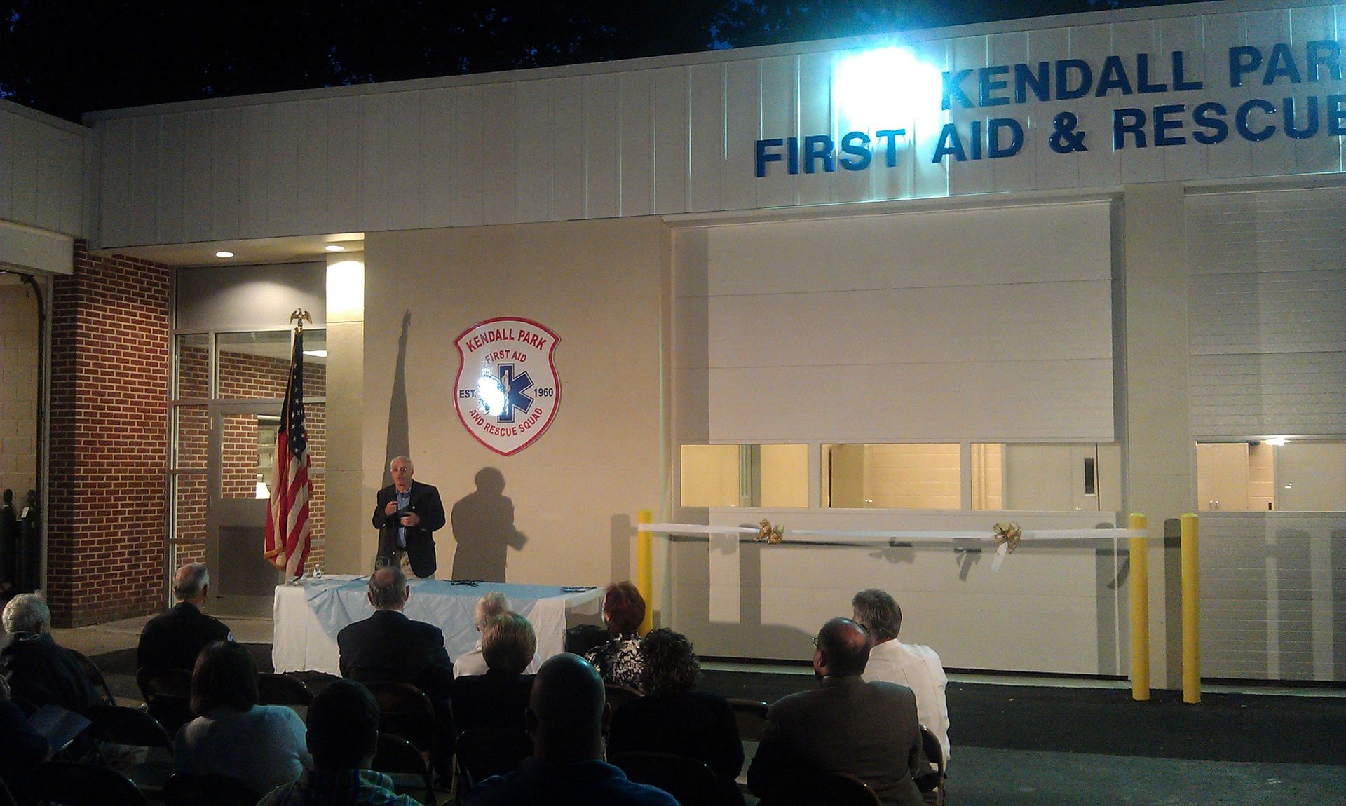 A speaker stands at a podium before an audience at a ribbon-cutting ceremony for the Kendall Park First Aid & Rescue.