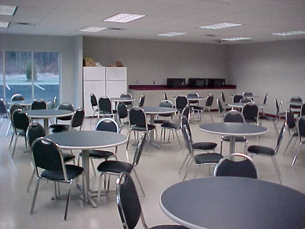 A modern, low-rise brick commercial building with a large grid-pattern glass window, red trim, and a centered entrance.