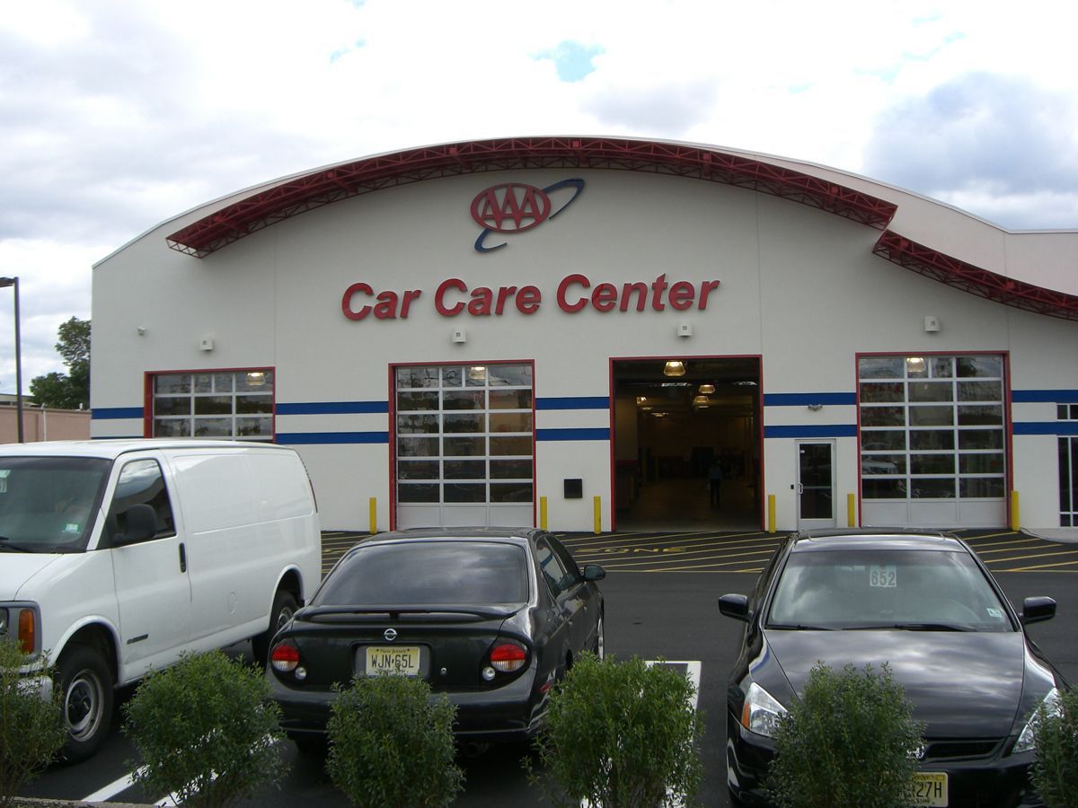 A stairwell with red railings and a large glass window wall overlooking a road, trees, and landscaping.