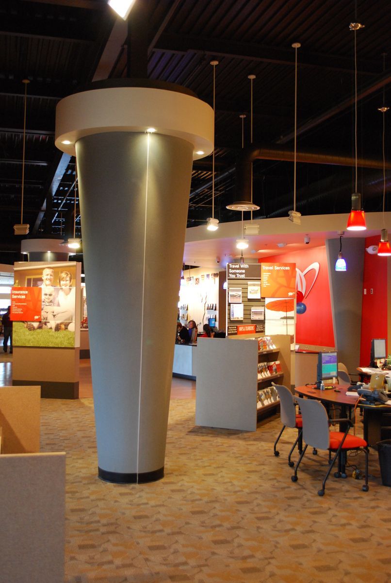 Modern two-story brick building with red-framed windows and doors under a blue sky with clouds.