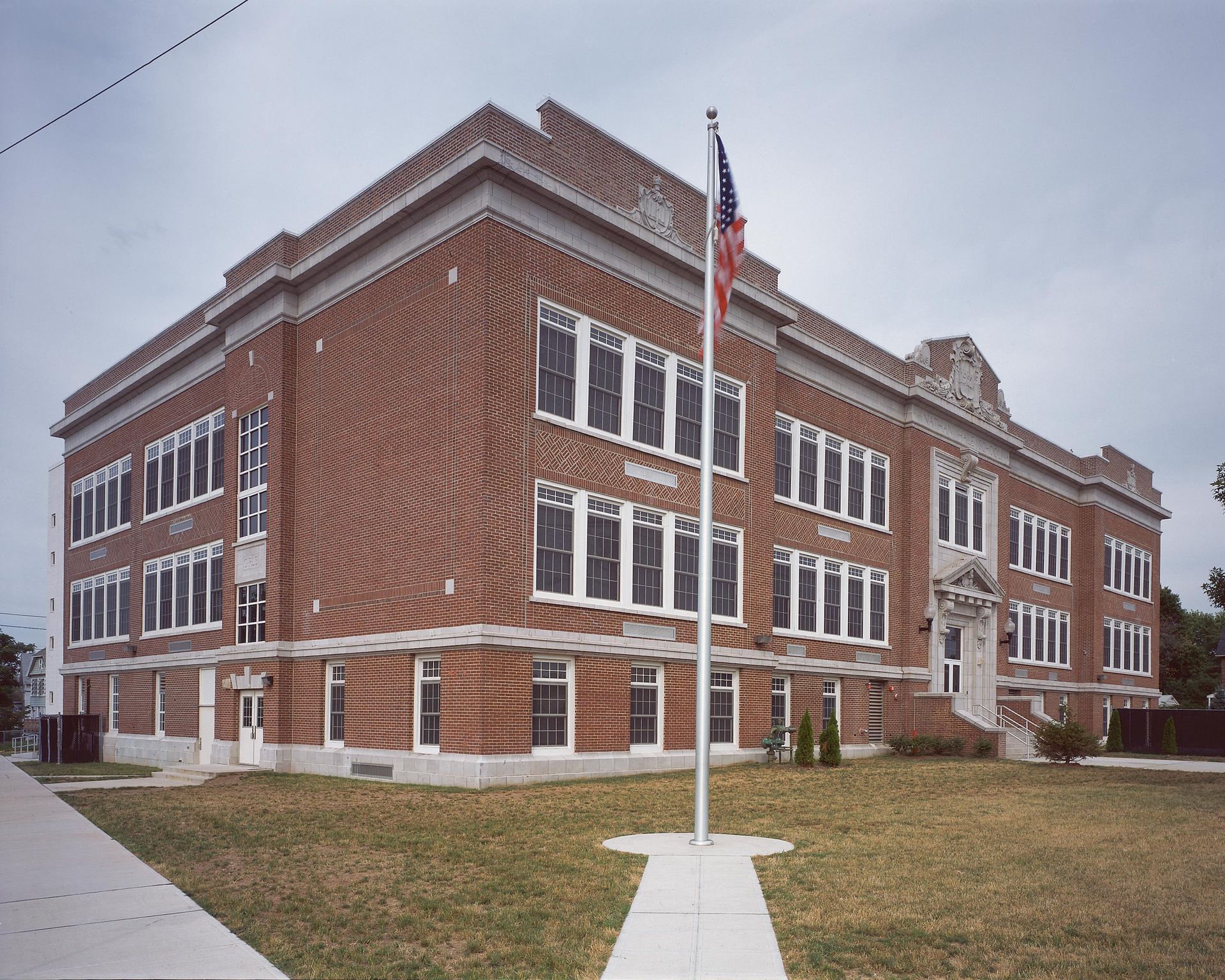 A stairwell with red railings and a large glass window wall overlooking a road, trees, and landscaping.