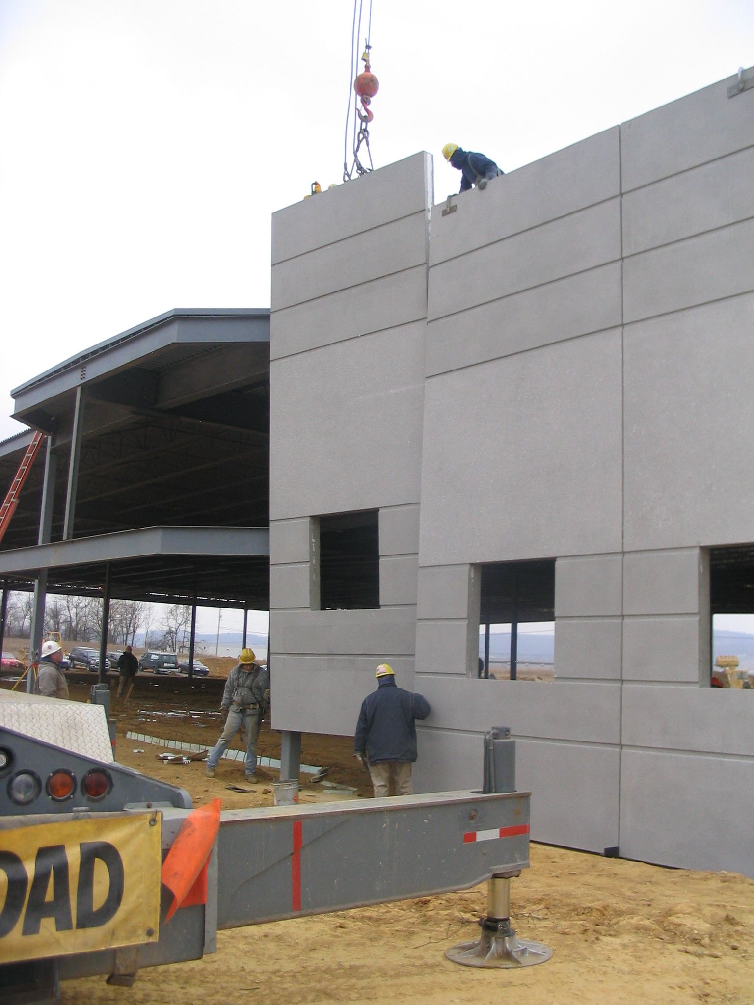 Modern two-story brick building with red-framed windows and doors under a blue sky with clouds.