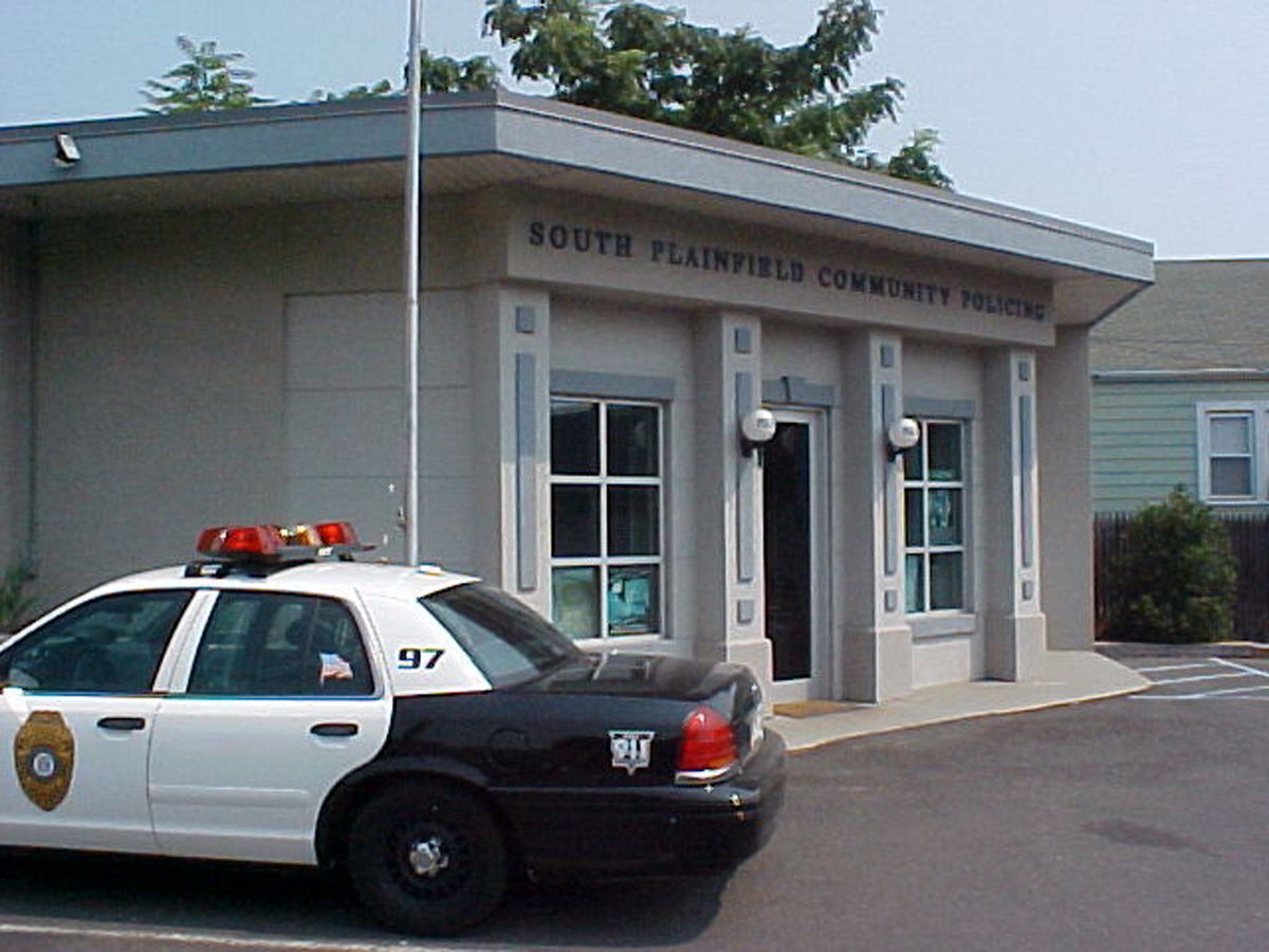 A police car parked in front of the South Plainfield Community Theater on a bright day.