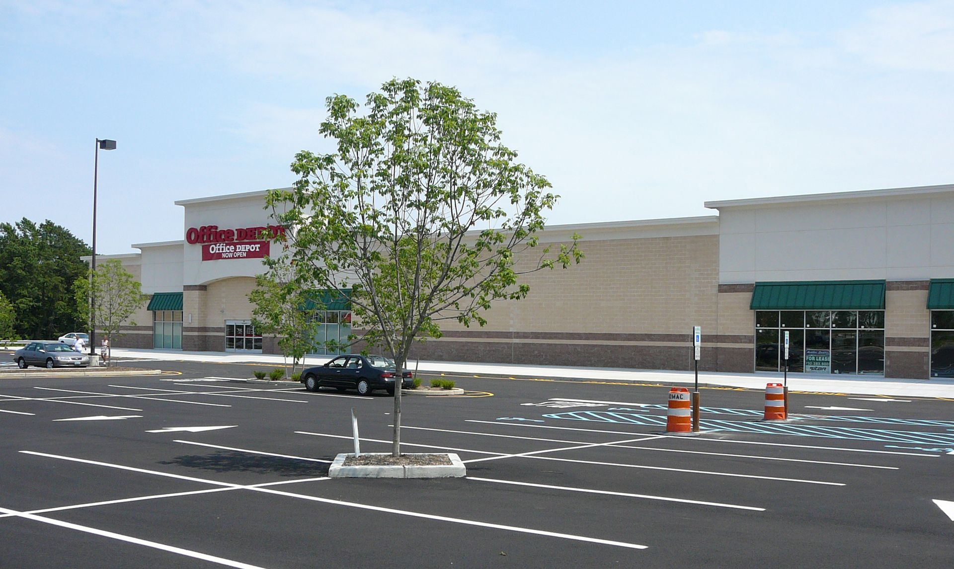 A stairwell with red railings and a large glass window wall overlooking a road, trees, and landscaping.