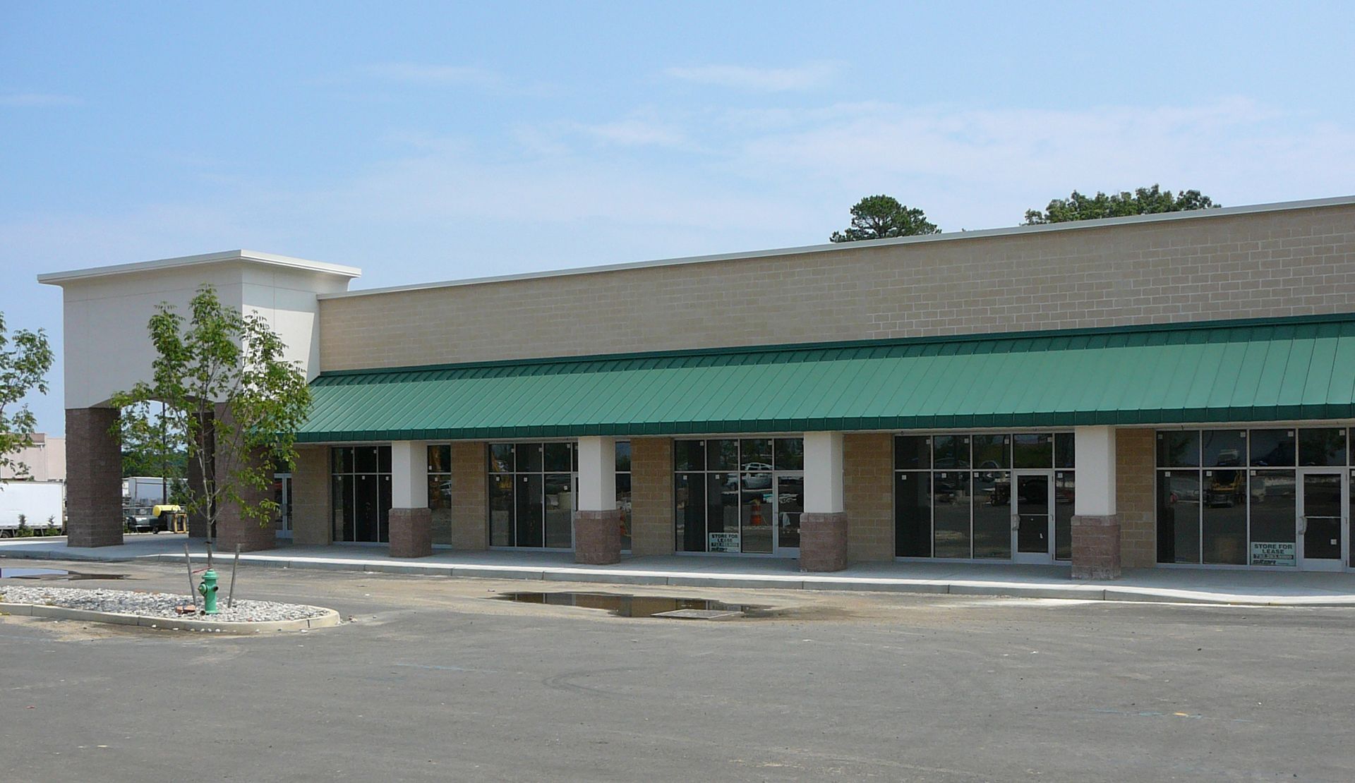 Modern two-story brick building with red-framed windows and doors under a blue sky with clouds.