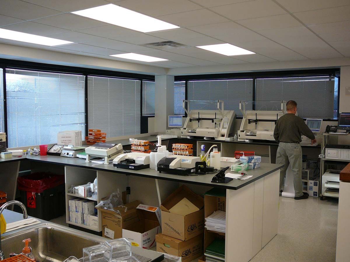 A break room with a small round table, two chairs, a counter with a sink, a coffee maker, and a microwave by a window.