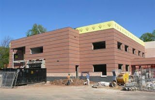 A two-story commercial building under construction with red-brown brick exterior walls and a yellow upper trim.