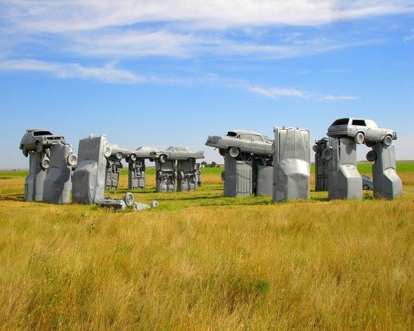 Carhenge, a sculpture made of gray vintage cars arranged in a circle to mimic Stonehenge, set in a rural grassy field.