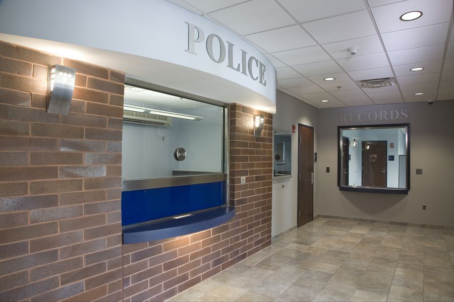 A modern police station lobby with a brick front desk labeled 