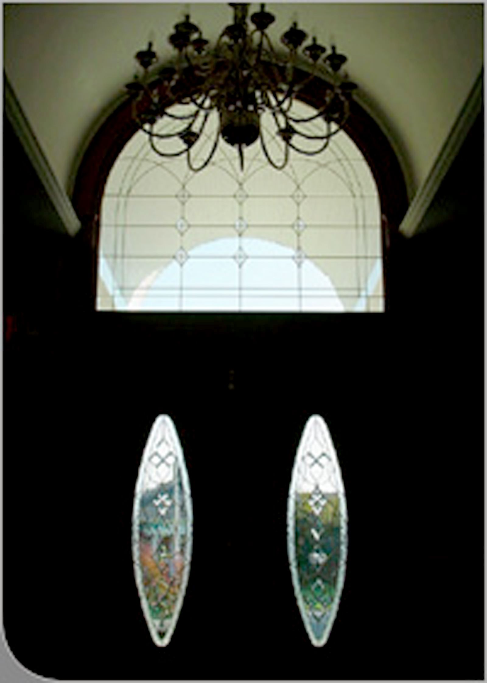 Modern two-story brick building with red-framed windows and doors under a blue sky with clouds.