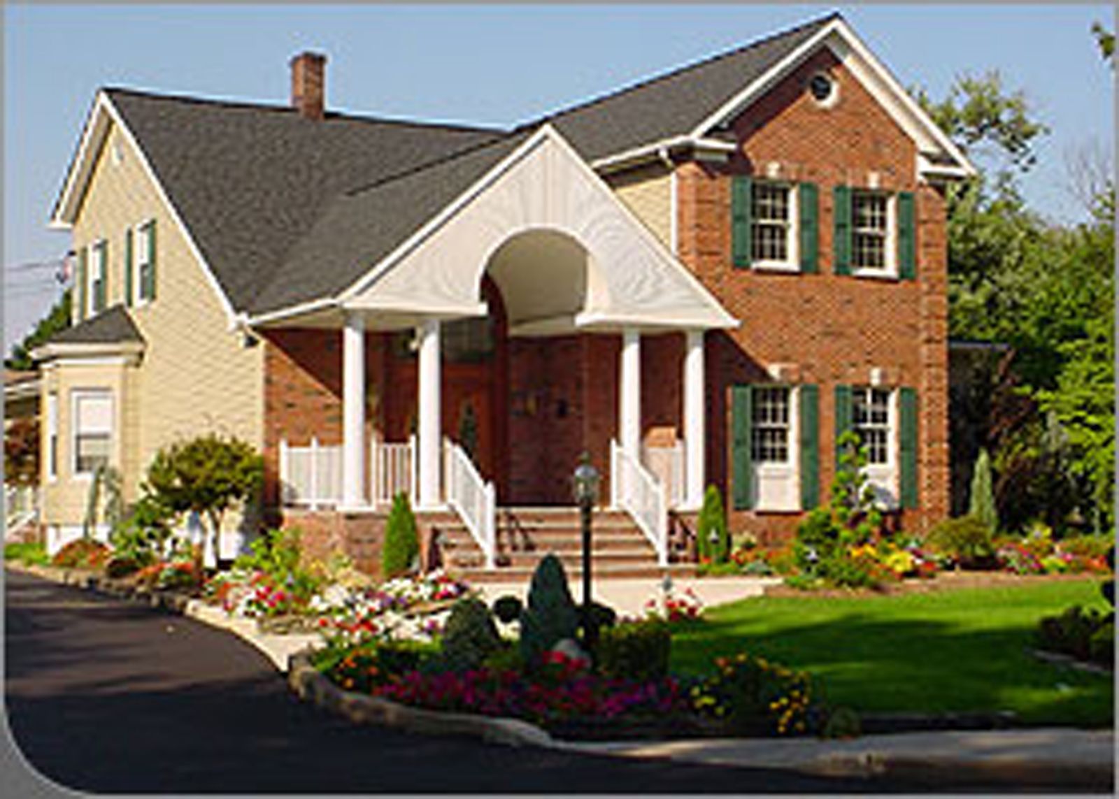 A stairwell with red railings and a large glass window wall overlooking a road, trees, and landscaping.
