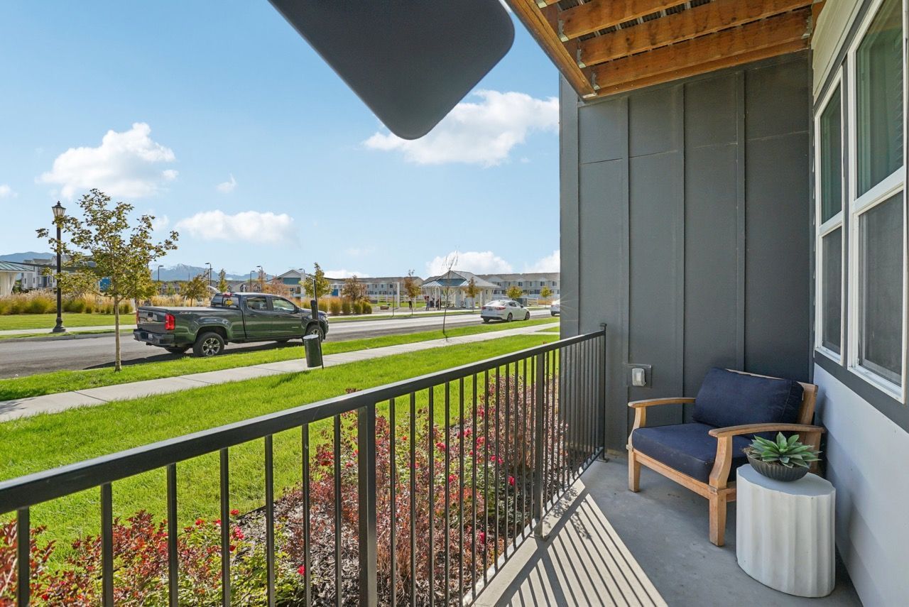 Balcony with chair overlooking a green lawn and street outside the apartment.