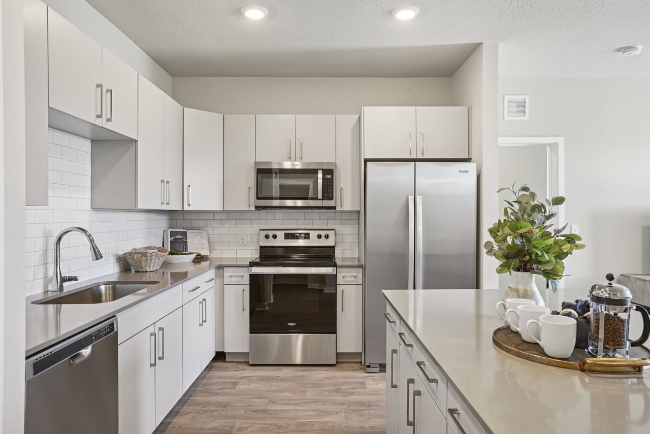 White modern kitchen with stainless steel appliances and an island.