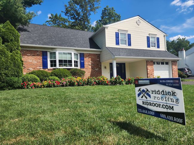 A house with a sign in front of it that says riddick roofing.