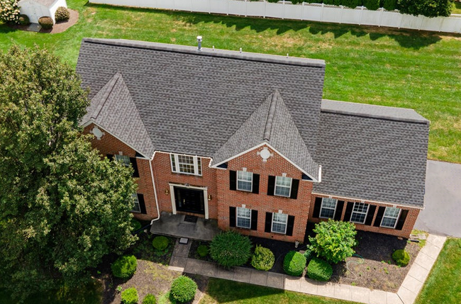 An aerial view of a large brick house with a gray roof.