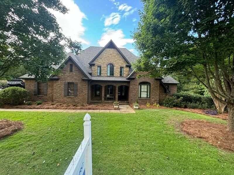 A large brick house with a white fence in front of it.
