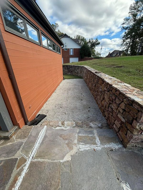 A brick building with a stone wall and a patio in front of it.