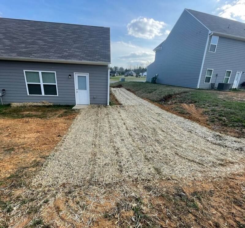 A dirt road leading to a house and a garage