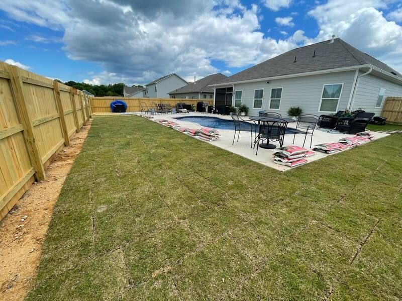 A backyard with a wooden fence and a swimming pool.