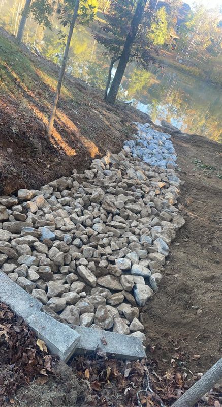 A path made of rocks is being built next to a river.