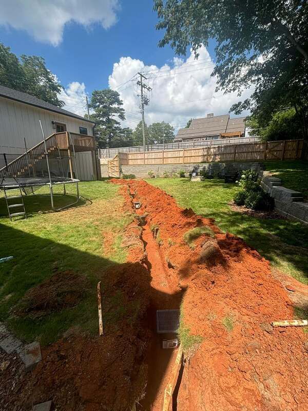 A large pile of dirt is in the backyard of a house.