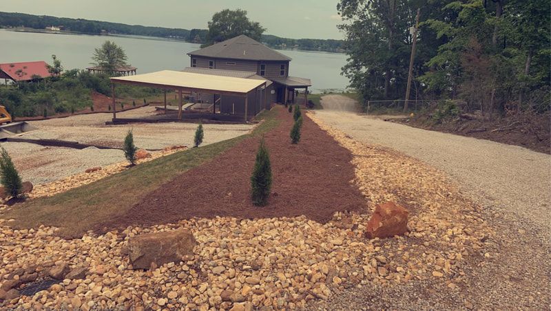 A gravel road leading to a house next to a lake.